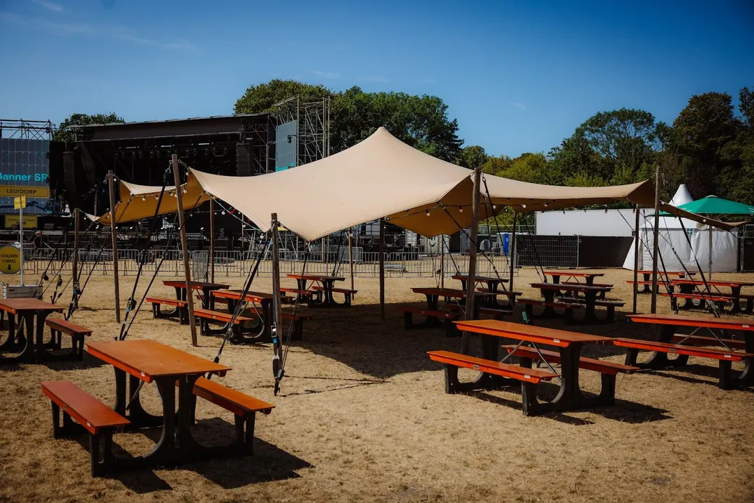 Picknicktafels in de schaduw van de zeilen